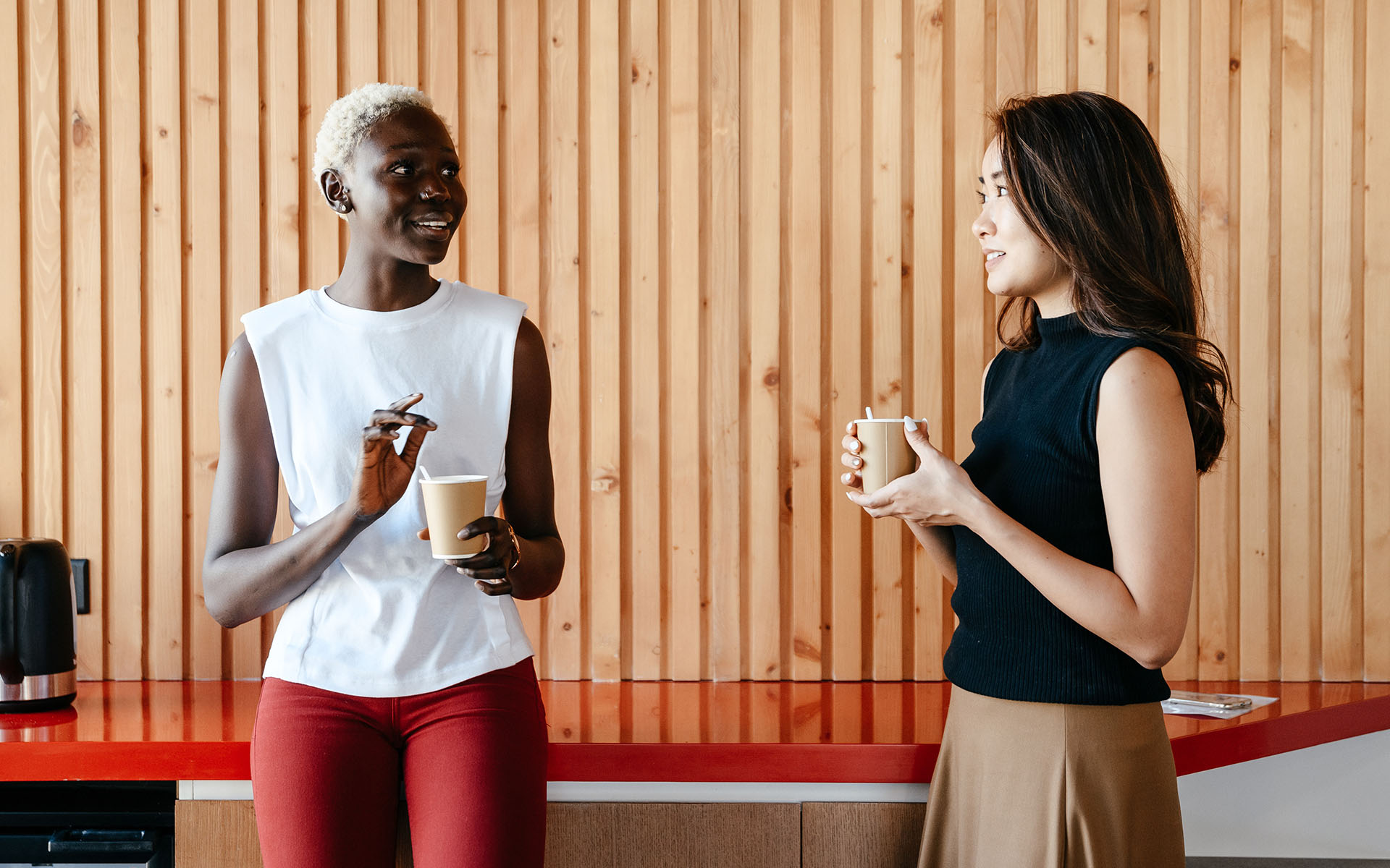 two colleagues talking over cups of coffee in a breakroom