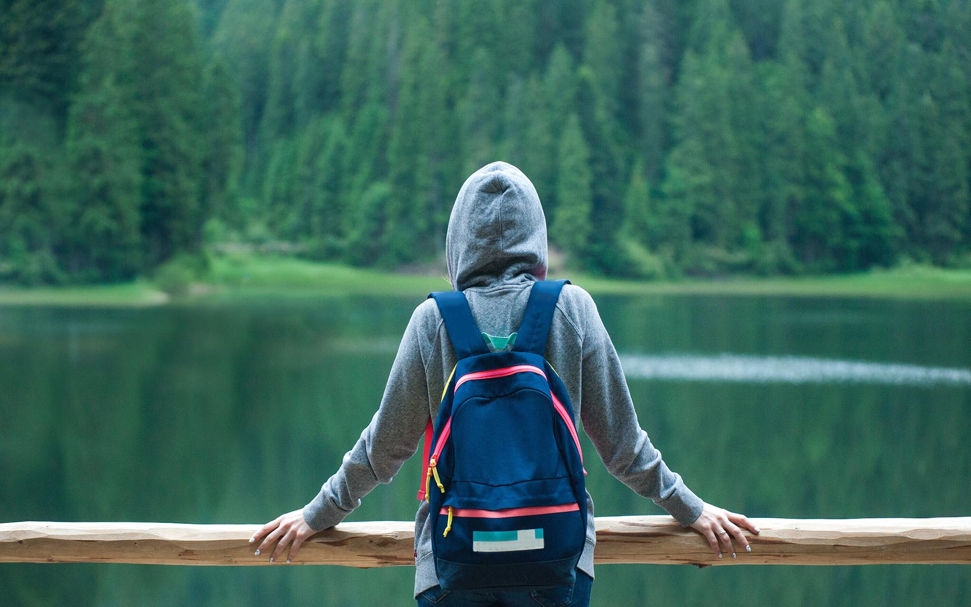 Person wearing hoodie looking into lake